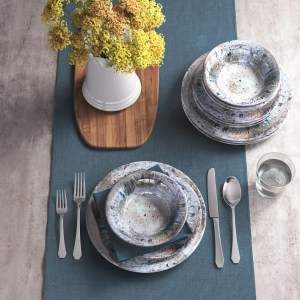 Table setting of glazed pottery, silverware and a vase of yellow flowers